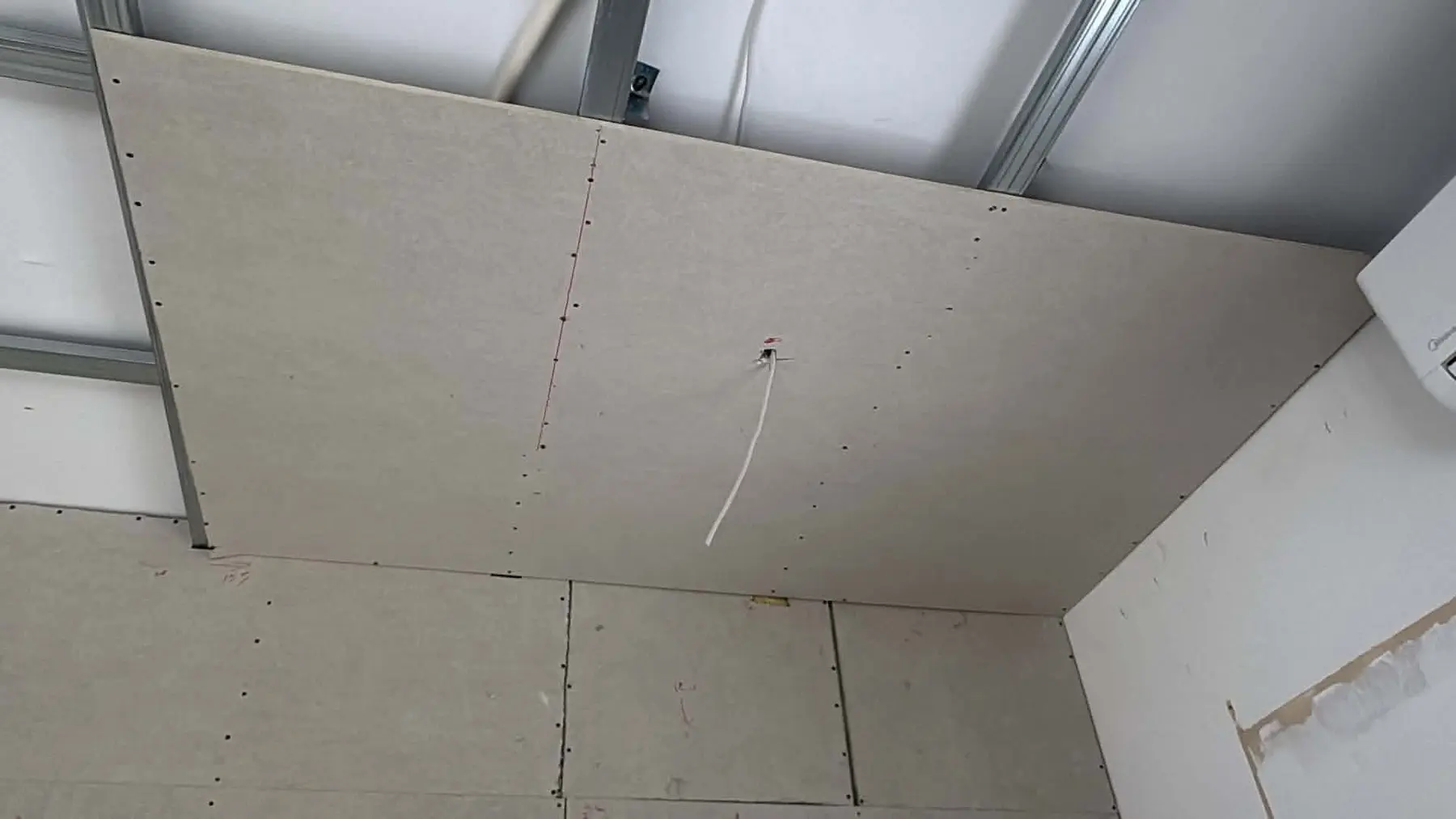 Gypsum boards being installed on a ceiling frame