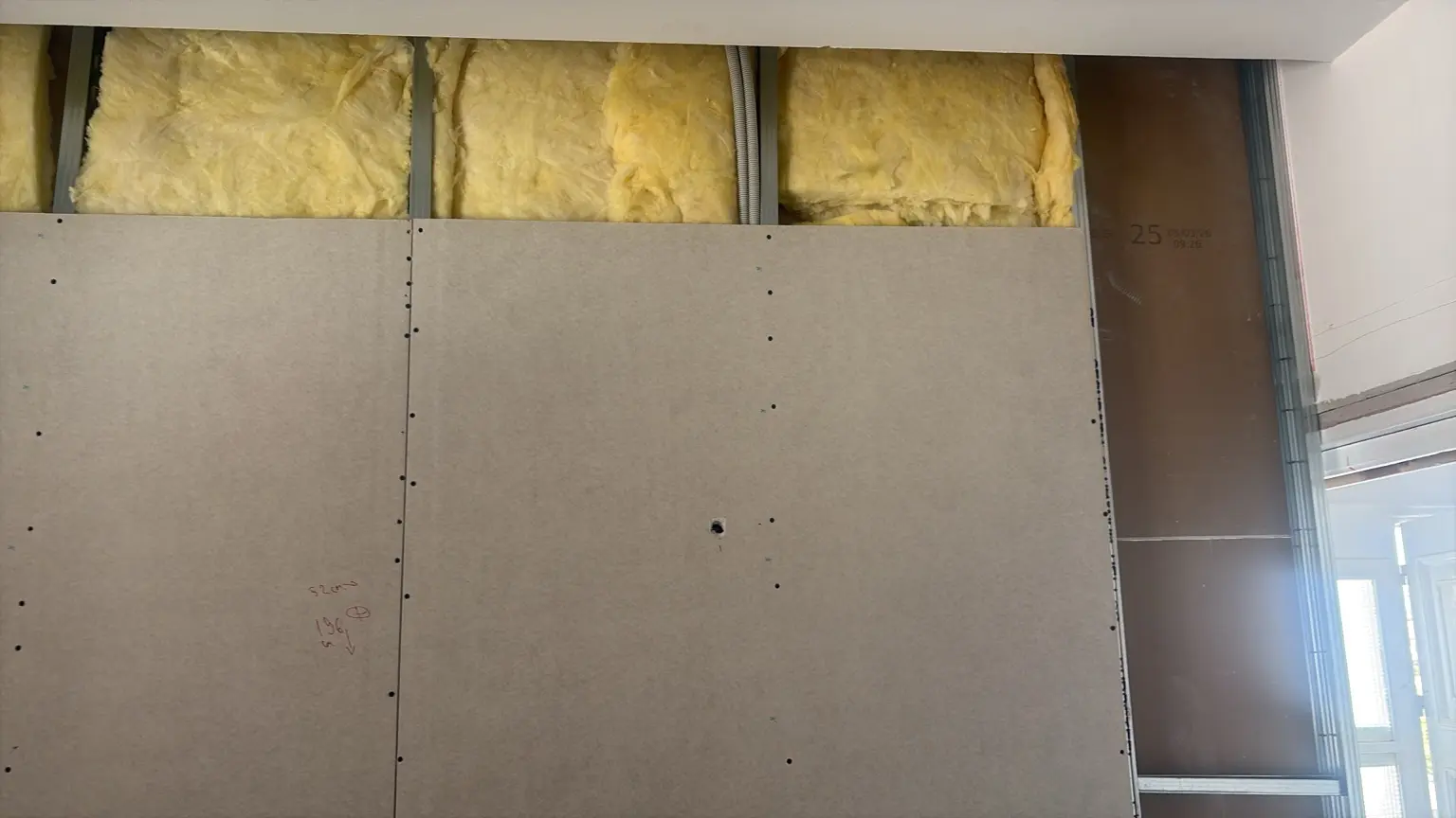 Insulation fitted inside an interior metal wall frame